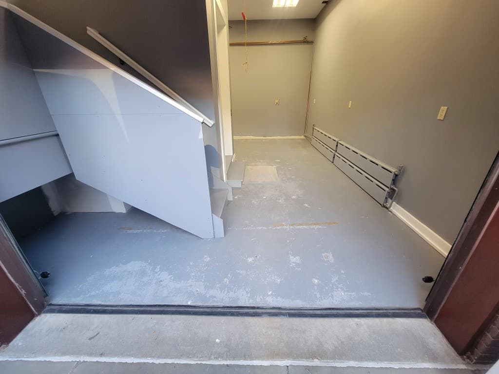 Bare concrete basement floor with old paint and stains before epoxy coating