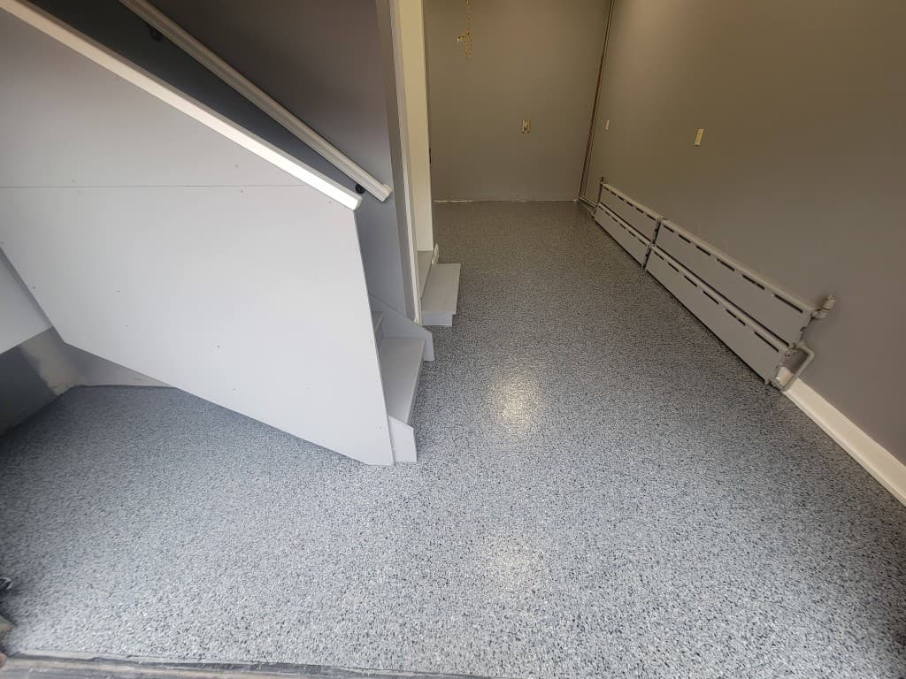 Finished basement with full-broadcast gray flake epoxy floor and staircase after installation