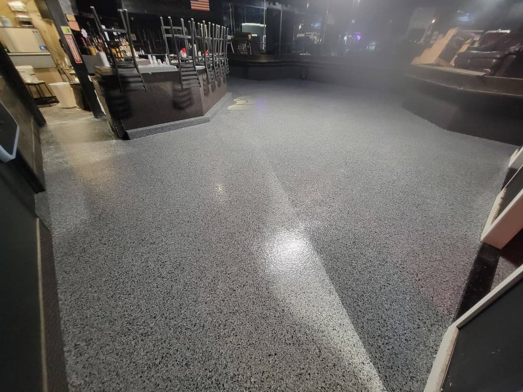 Same bar with dark full-broadcast flake epoxy floor after professional installation