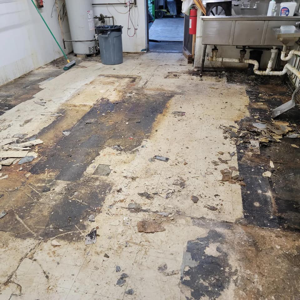 Demolished floor with old tile debris and damage before epoxy coating