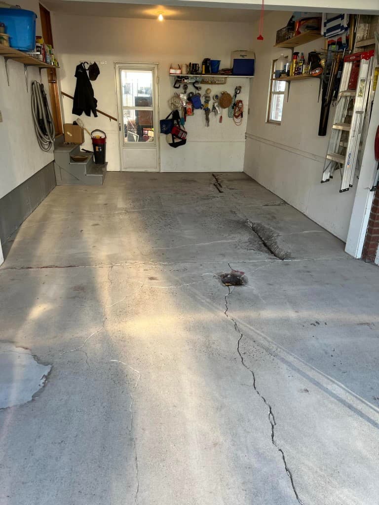 Garage concrete floor with cracks and damage before epoxy coating