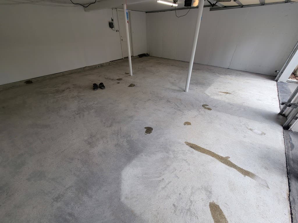 Bare concrete garage floor with oil stains before epoxy coating